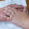 bride and groom pose with hands on marriage license