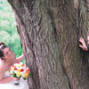bride and groom peeking around tree trunk